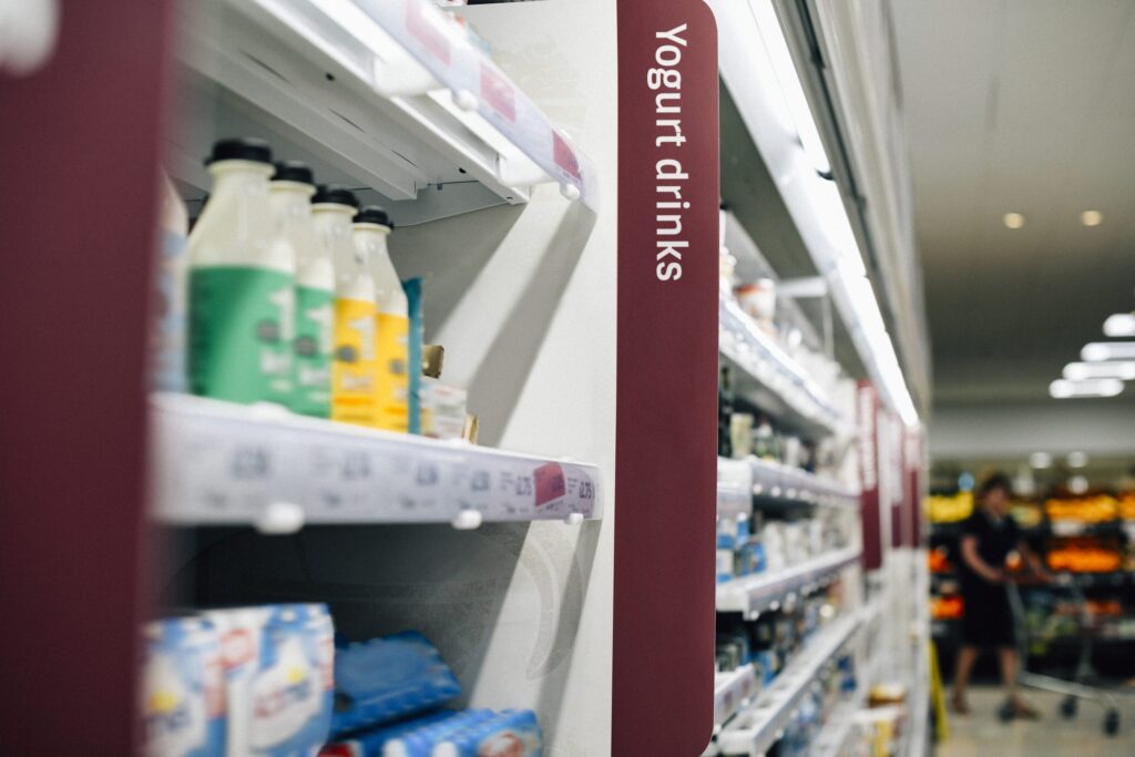 Retail media nel supermercato: scaffale fisico con bottigliette di yogurt da bere e fascia verticale sullo scaffale
